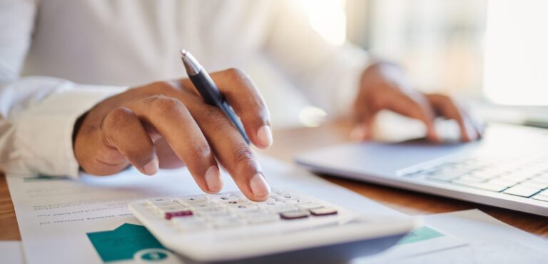 A man on a computer and calculator working out his business budget strategy.
