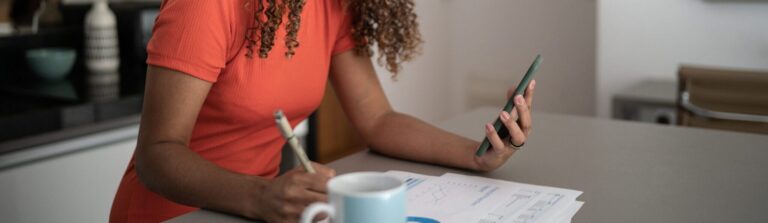 Woman doing home finances and using mobile phone at home