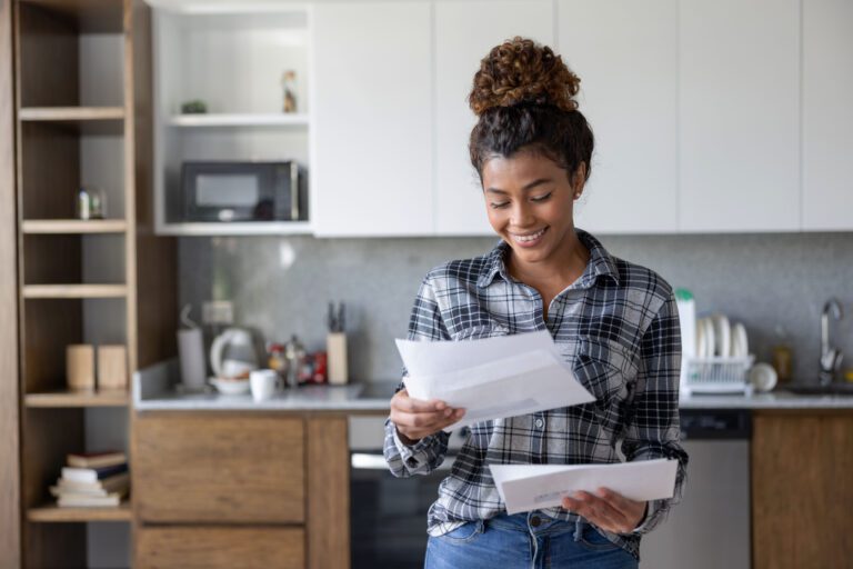 Smiling woman at home reviewing her mail