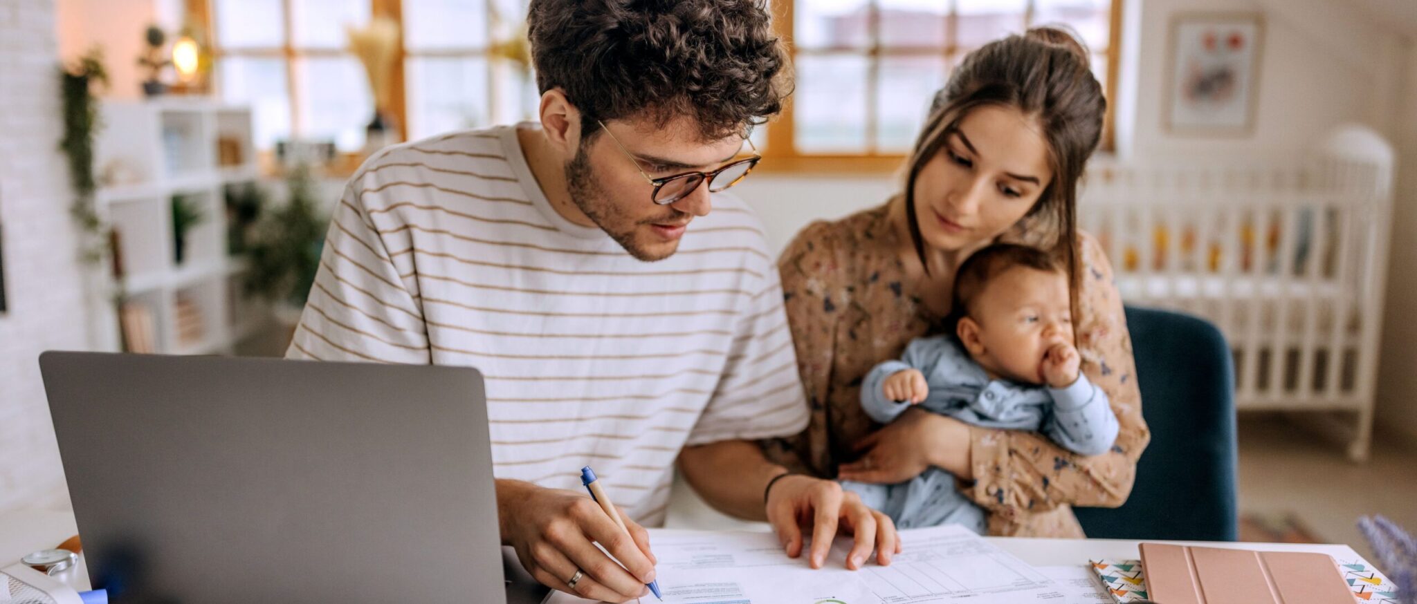 Young family with baby boy going over finances at home and creating a budget.