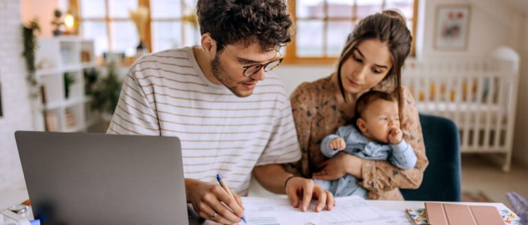 Young family with baby boy going over finances at home and creating a budget.