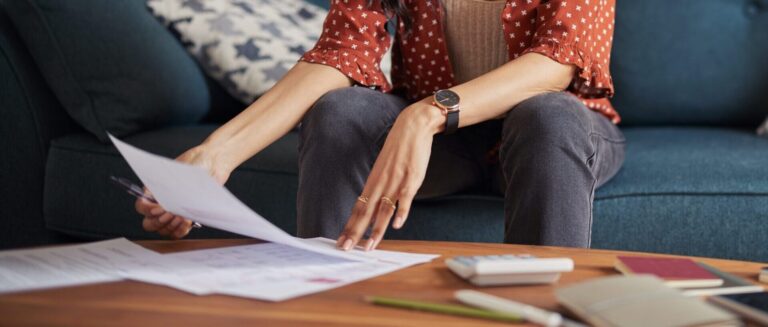 Focused young woman reviewing financial documents at home
