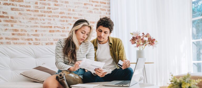 young couple paying bills at home on their computer