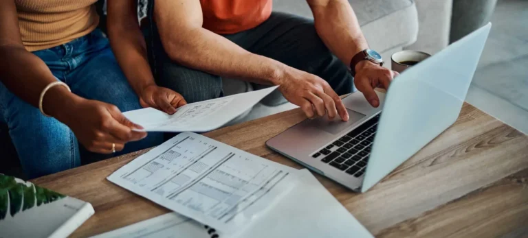 A couple sitting in the living room and using a laptop to calculate their finances