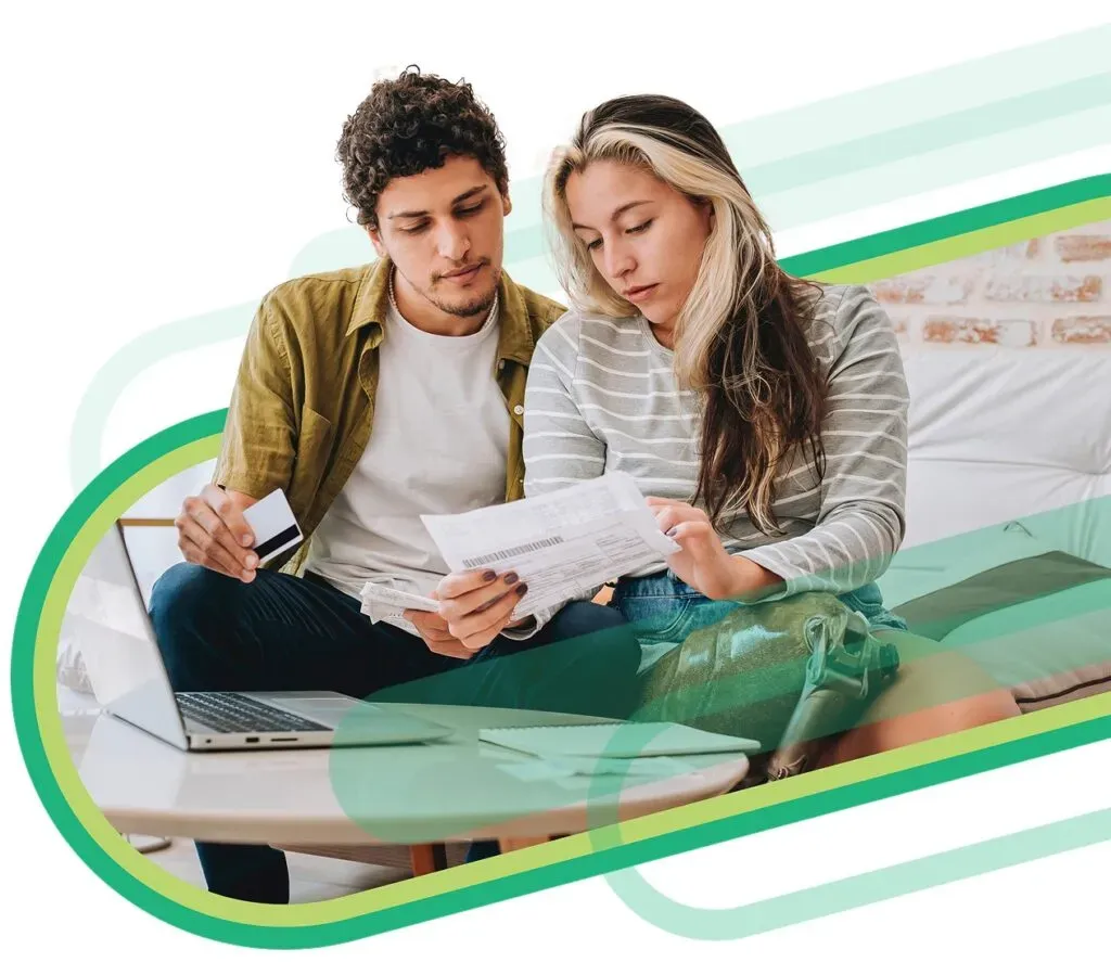 Young, trendy couple sitting on a coach reviewing a bank statement