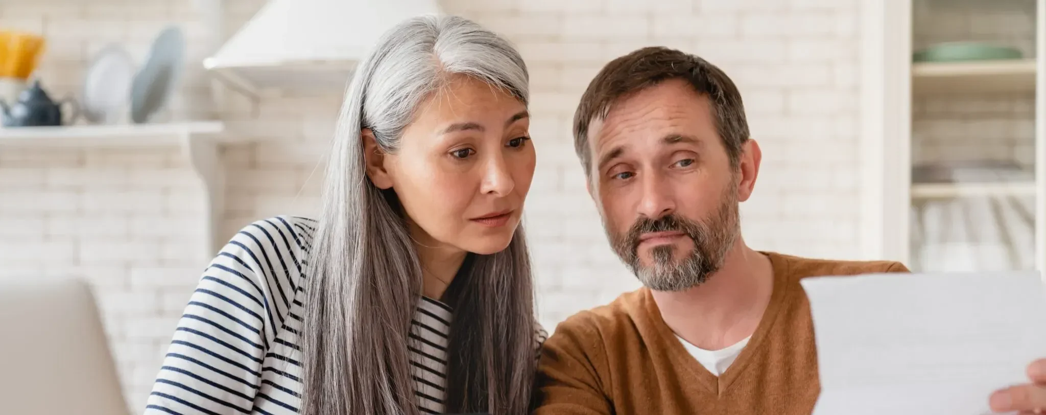Mature middle-aged couple wife and husband doing paperwork with calculator and laptop