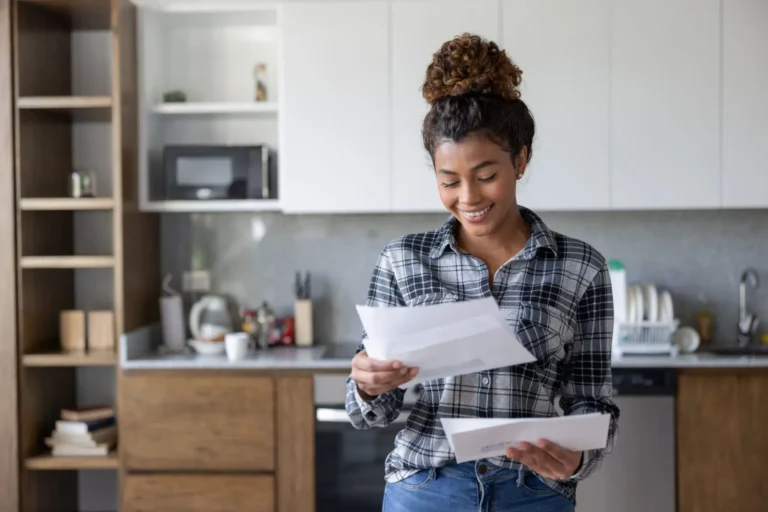 Smiling woman at home reviewing her mail