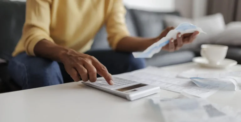 Close up of an adult woman calculating her bills at home, sitting in her living room.