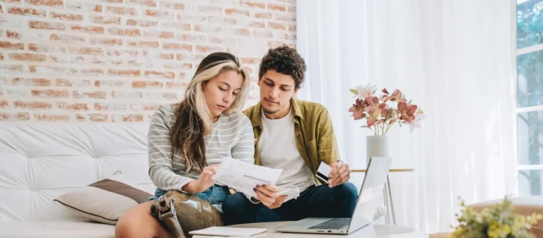 young couple paying bills at home on their computer