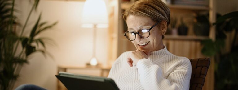 A smiling mature woman using a tablet at night