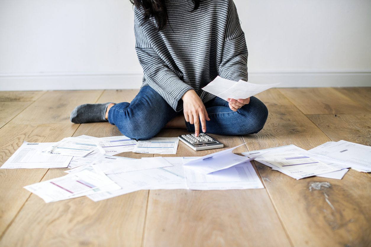 Woman on the floor with calculator and bills